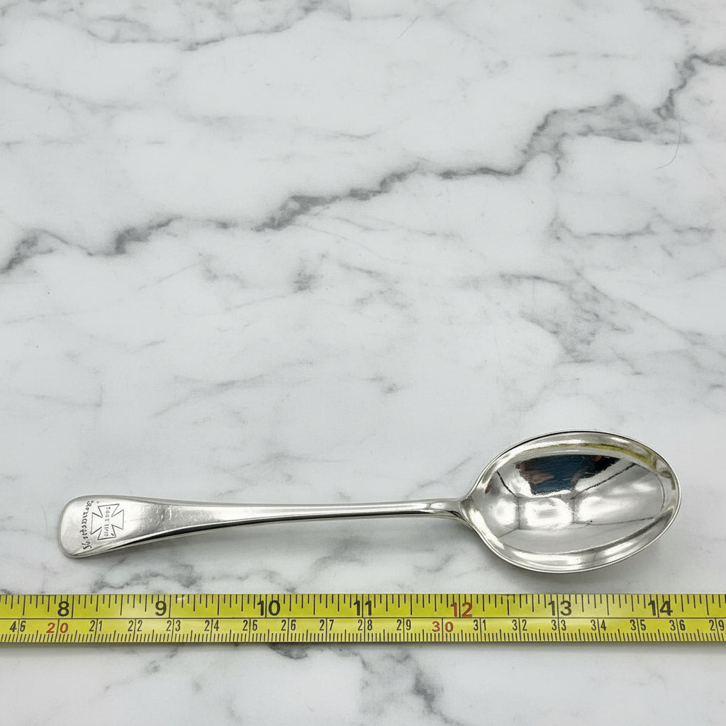 Antique Silver plated spoon with Marjorie on the handle next to a tape measure on a marble worktop