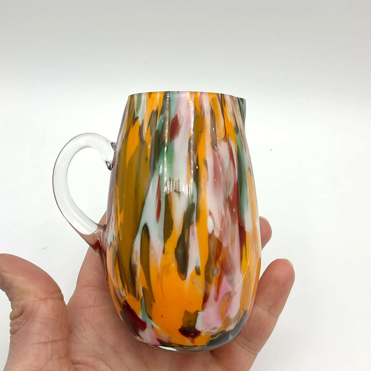 Small handmade vintage art glass cream jug by Beeches Vintage with a delicate, colorful design and smooth curved handle.