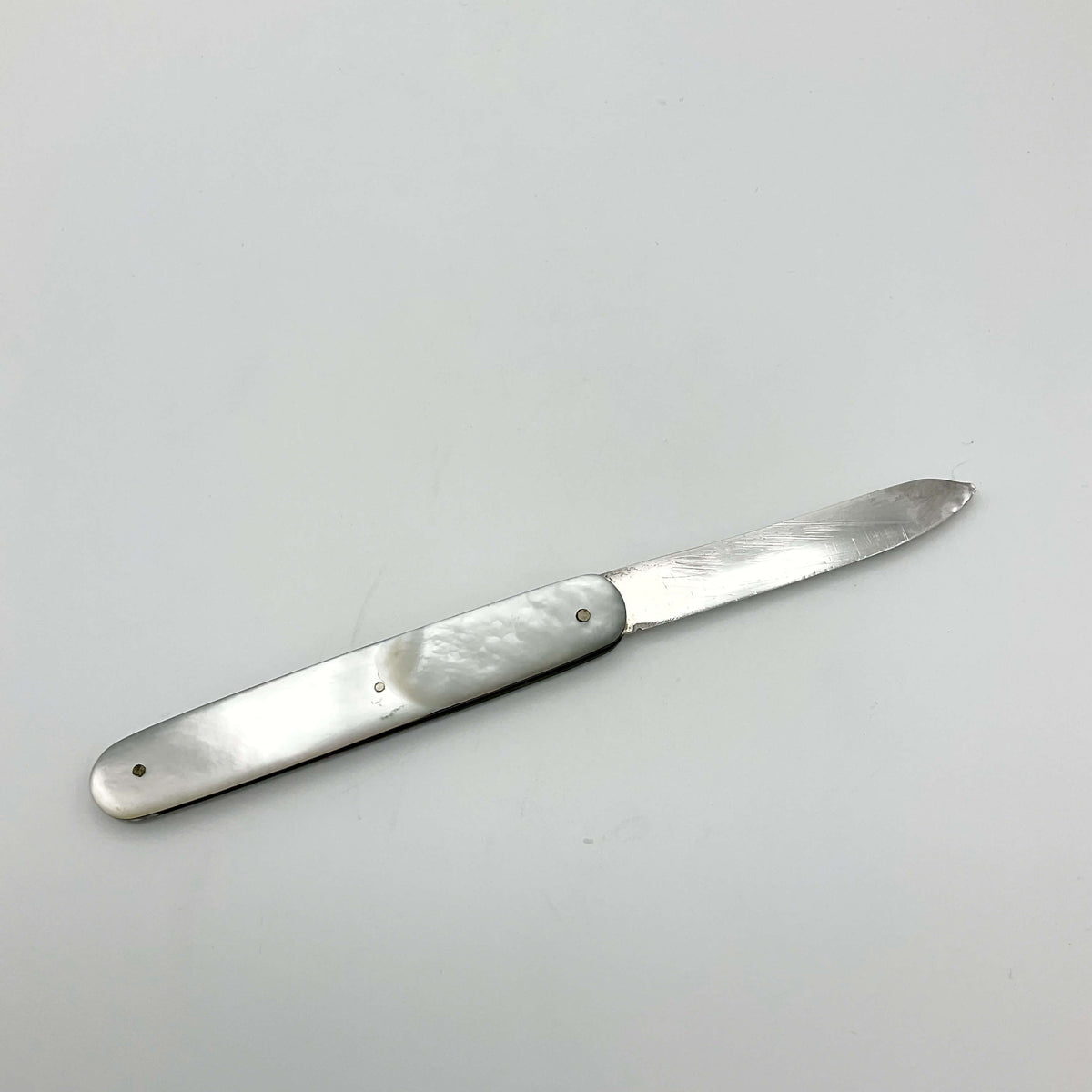 Silver fruit knife with a mother of pearl handle on a white background 