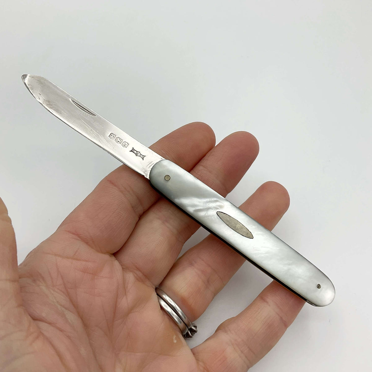 Silver fruit knife with a mother of pearl handle on a hand