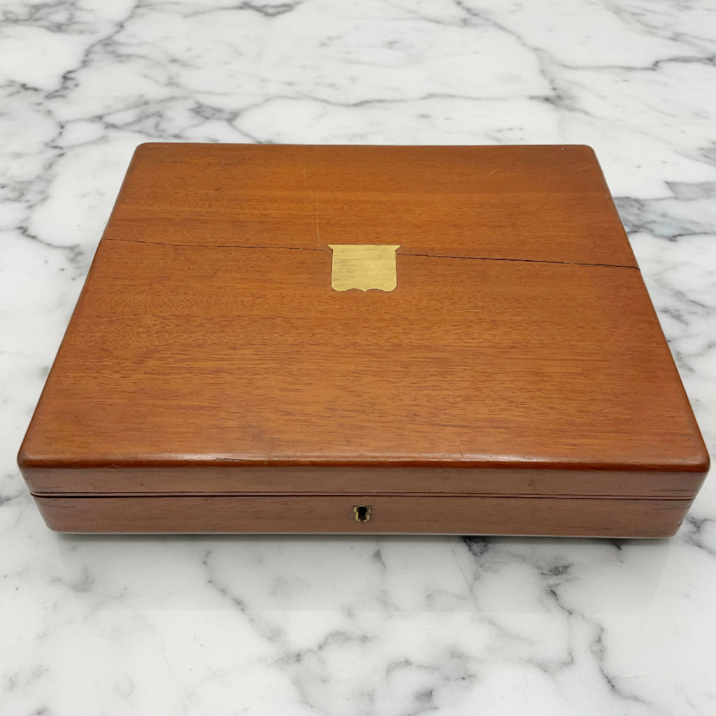 Antique wooden box with a brass shield in the centre on a marble background