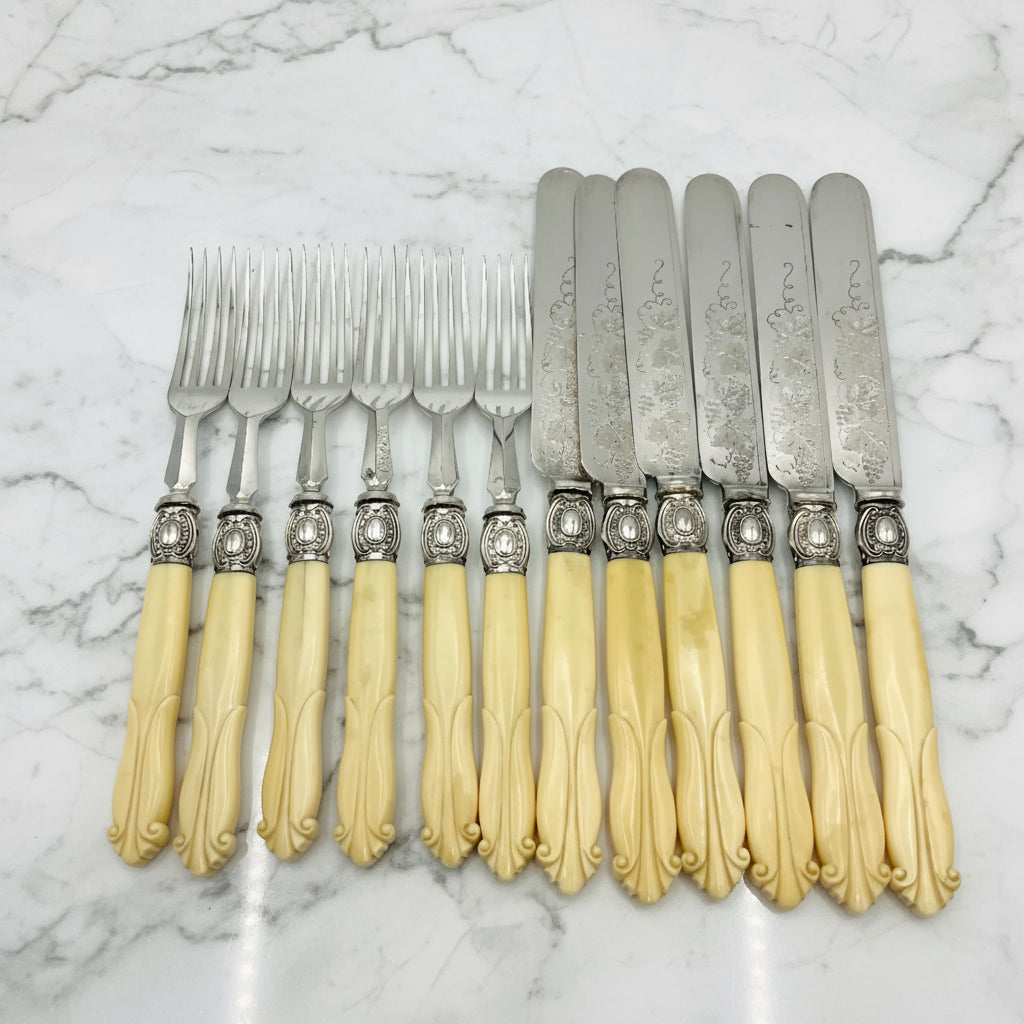 Antique silver plated dessert knives and forks with bone handles on a marble background