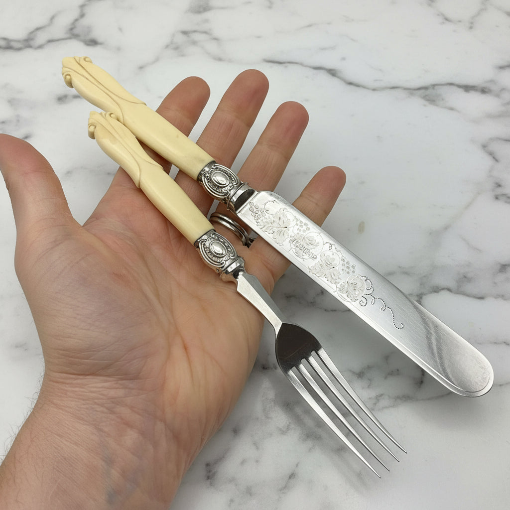 an antique silver plated knife and fork with bone handles held in a hand