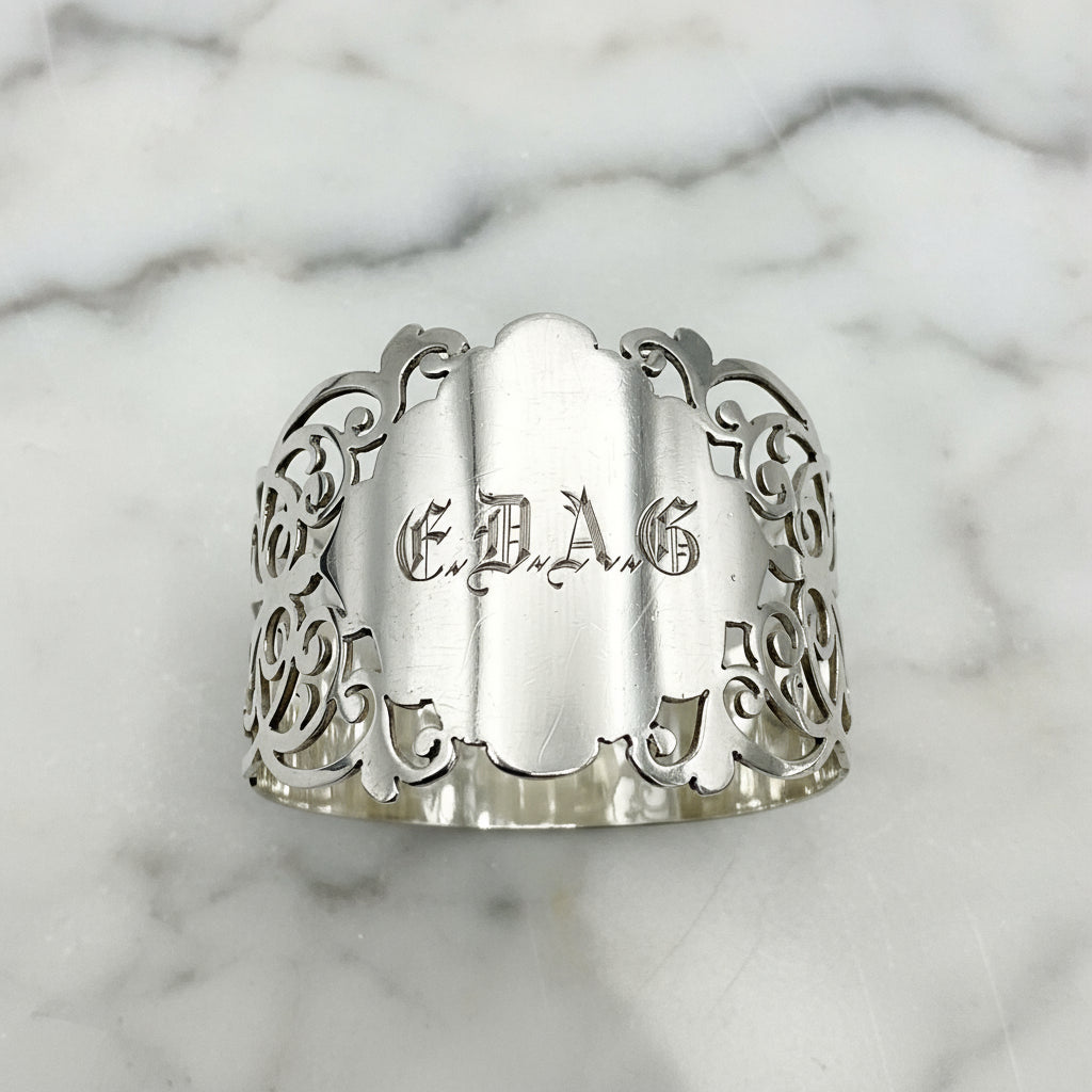 Shiny napkin ring with elaborate sides and EDAG in the centre on a marble background 