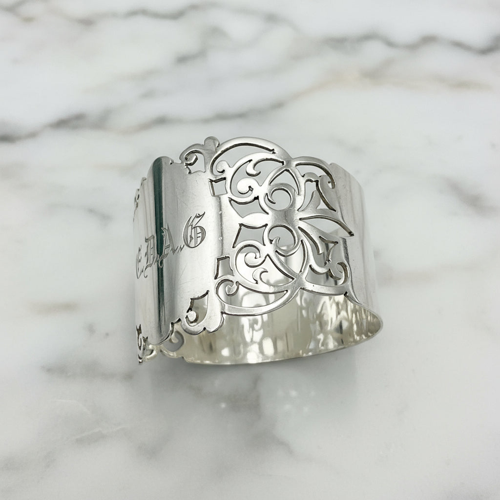 Shiny napkin ring with elaborate sides and EDAG in the centre on a plain background 