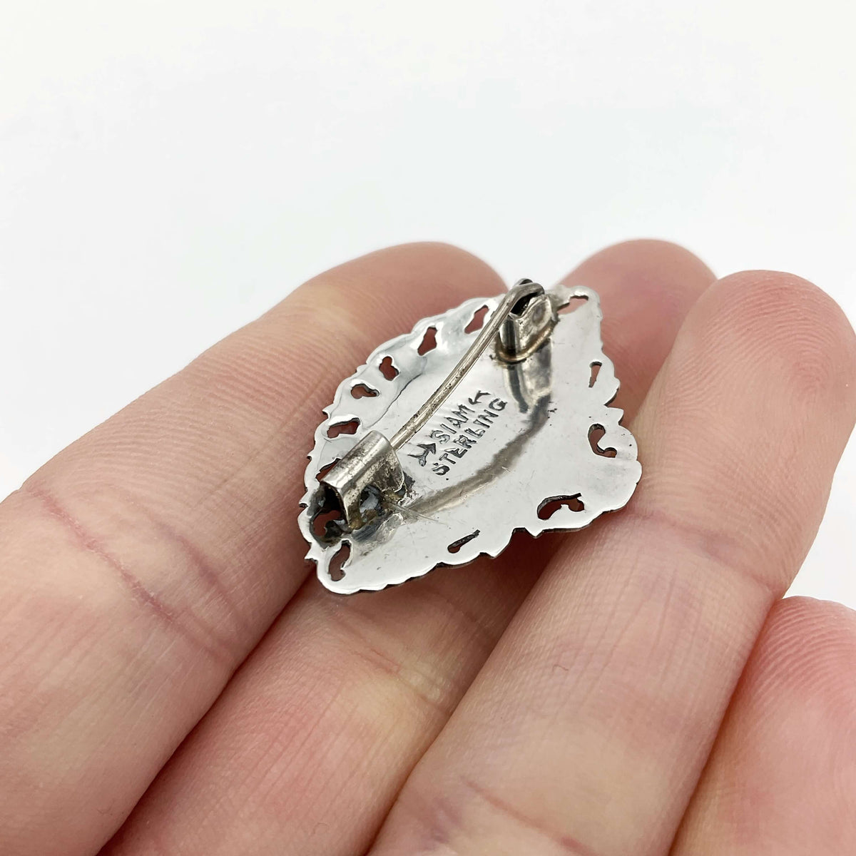Beautiful Silver Niello Brooch back view showing Siam Sterling on the back. Held in a hand.