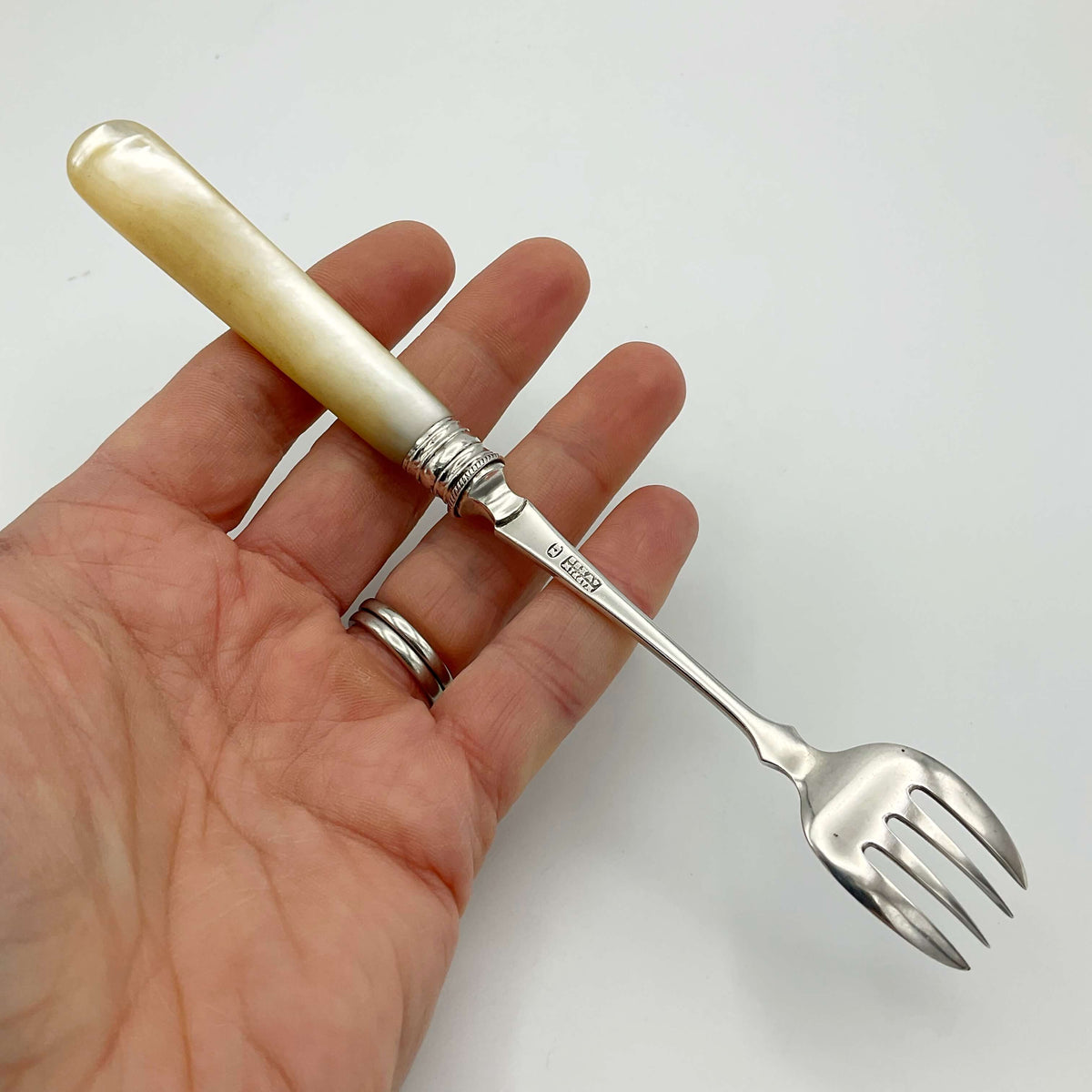 Vintage silver-plated pickle fork with a mother of pearl handle by Beeches Vintage, showcasing elegant craftsmanship and detailed design.