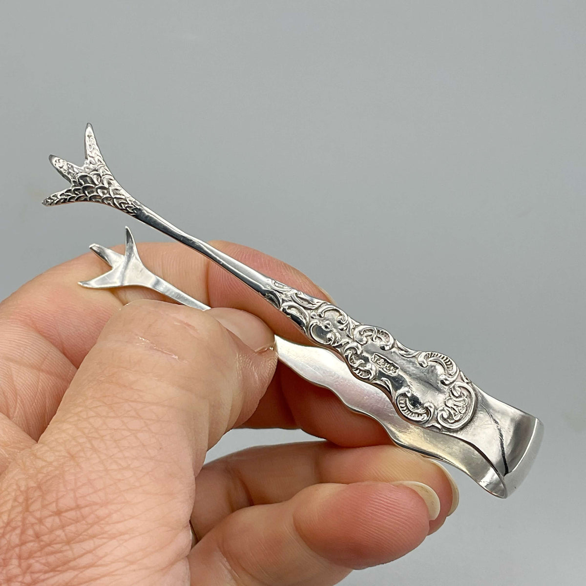 Antique 1902 small sterling silver sugar tongs by Beeches Vintage, featuring intricate design and classic craftsmanship.