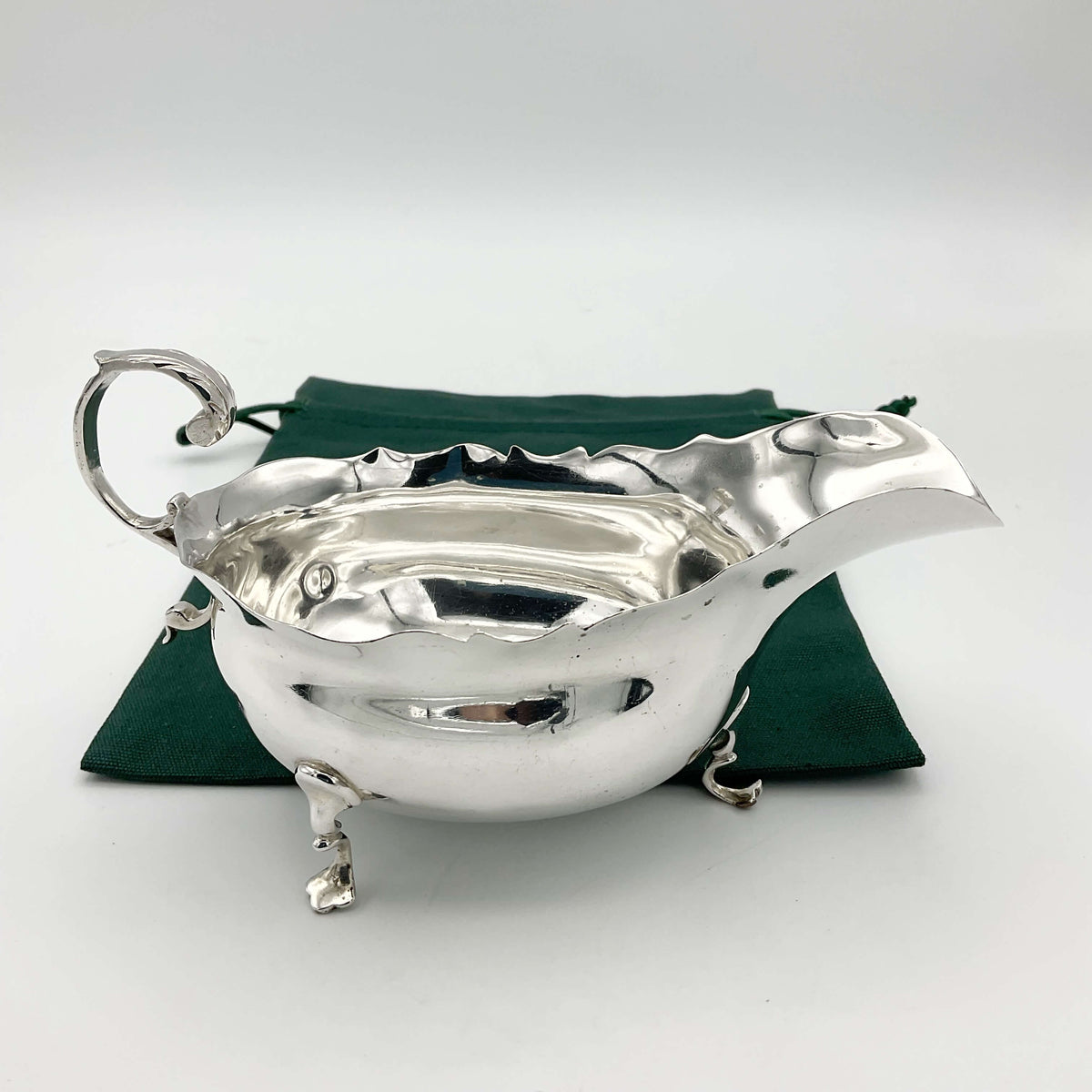 Antique 1902 solid silver sauce boat with ornate detailing, crafted by Beeches Vintage, displayed on a wooden surface.