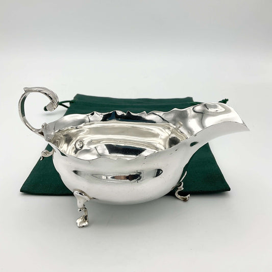 Antique 1902 solid silver sauce boat with ornate detailing, crafted by Beeches Vintage, displayed on a wooden surface.