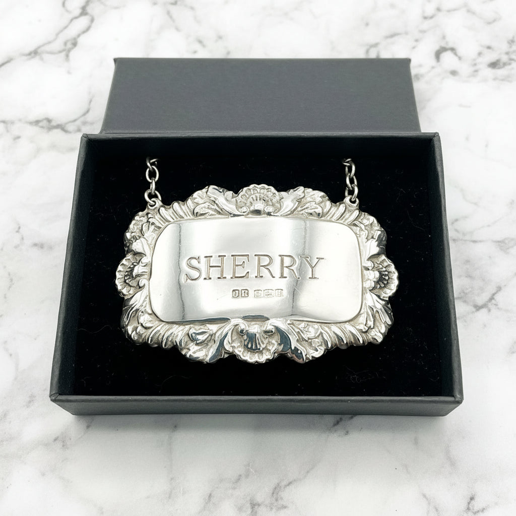 A shiny Sherry decanter label in a black presentation box on a marble background.