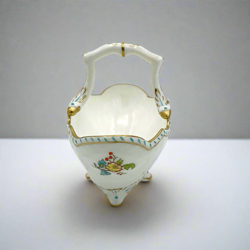 end of china basket ornament showing painted flowers on a white table
