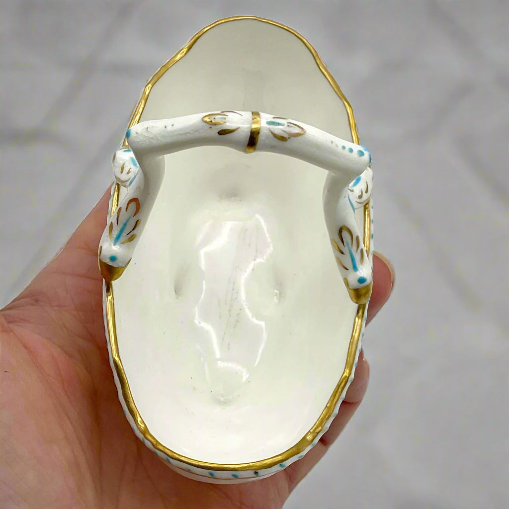 Inside of china basket ornament held in a hand with a grey blurred background