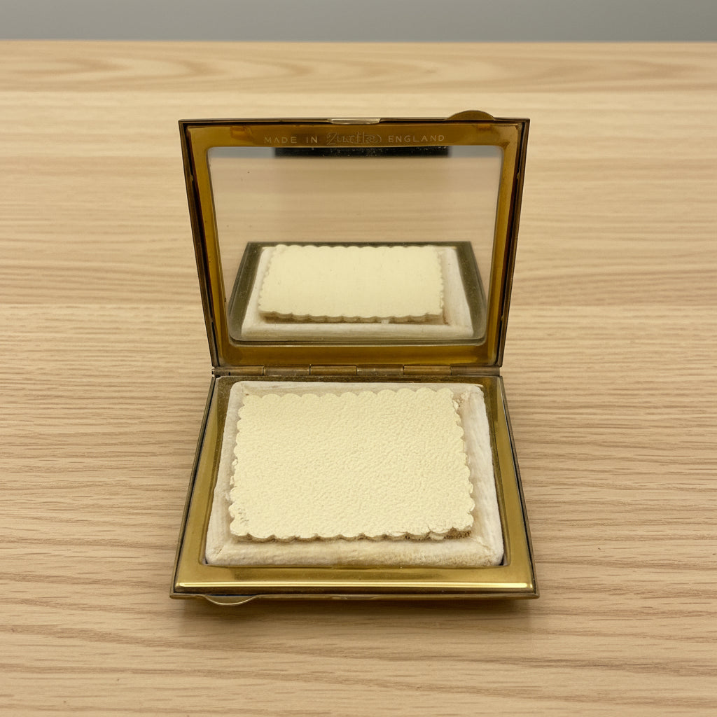 open poder compact with mirror and powder puff on wood table