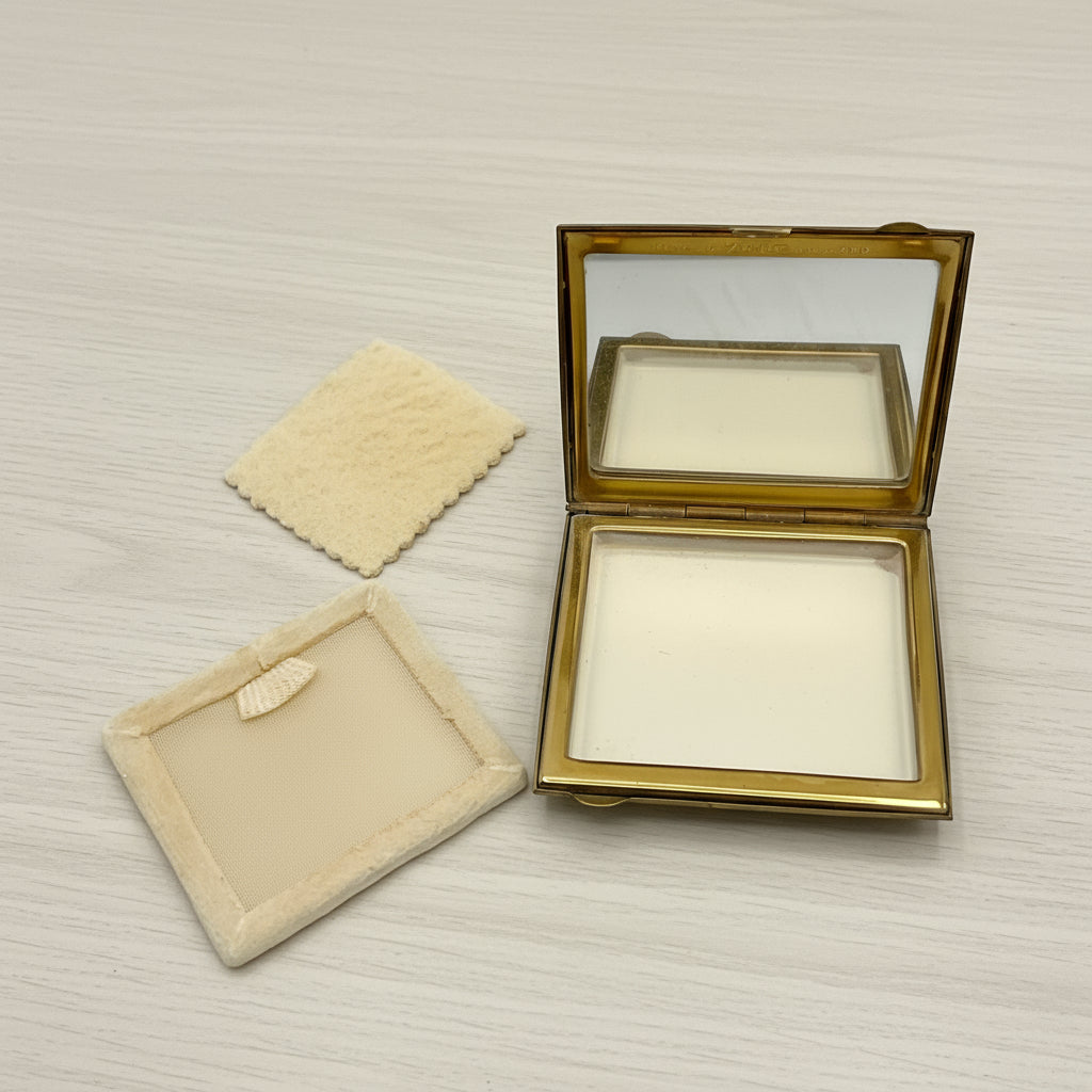 powder compact open with powder puff and powder screen on a wood table