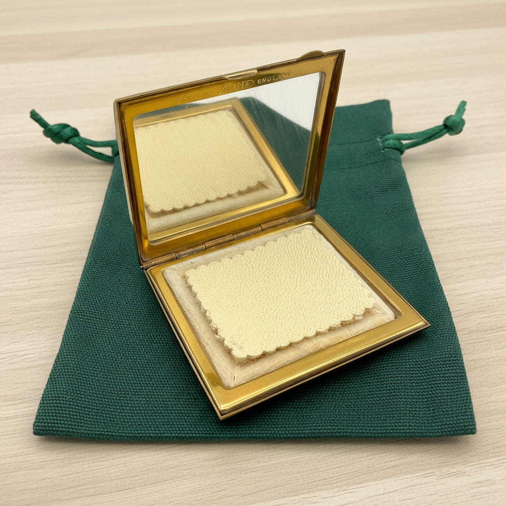 open powder compact on a green bag on a wood table
