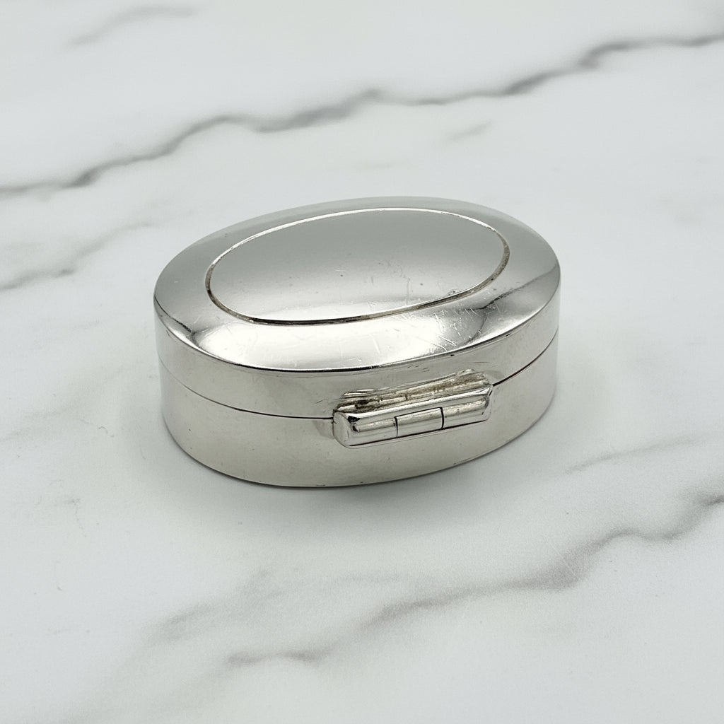 Silver oval pill box on a marble surface