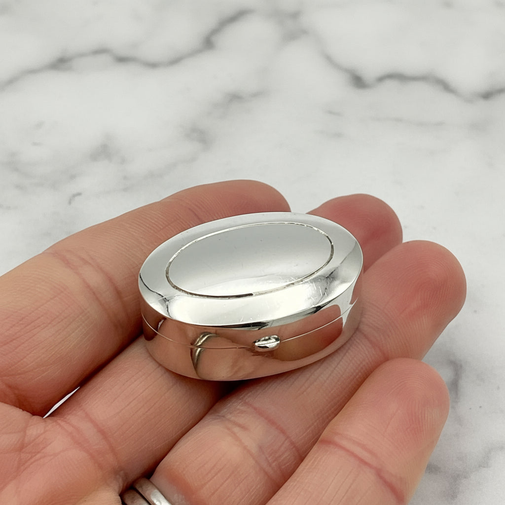 silver pill box in hand with a marble surface background