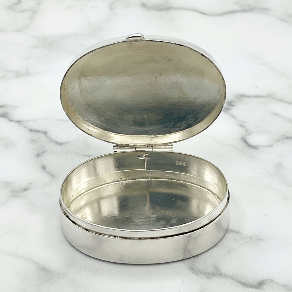 Silver pill boxvwith lid open on a marble worktop