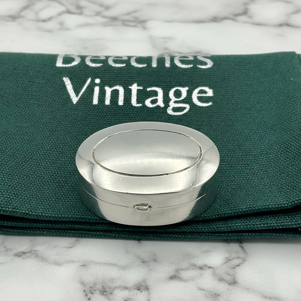 Silver pill box on a green gift bag and marble worktop