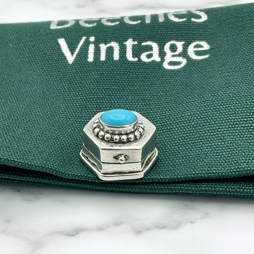 small pill box on green bag on marble surface