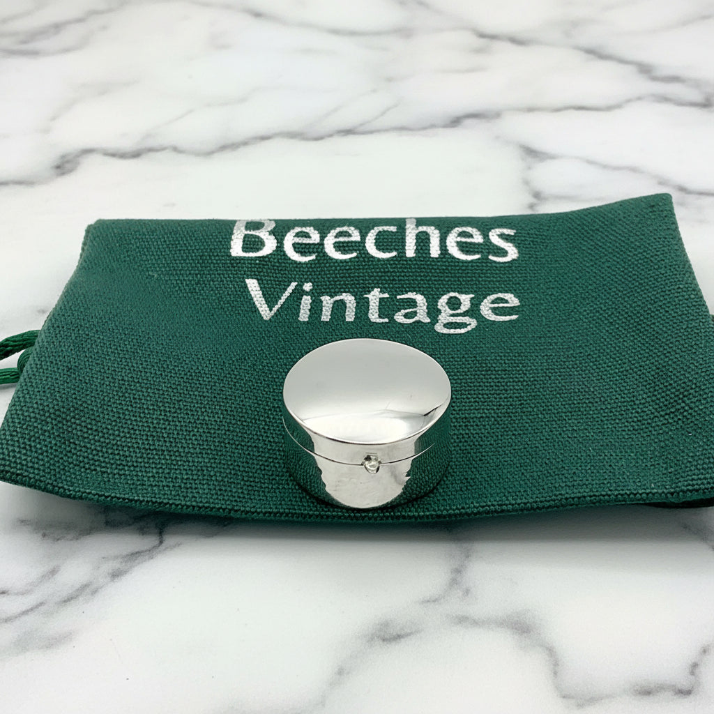 silver pill box on a green bag and marble worktop