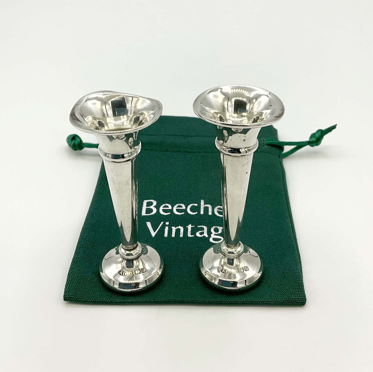 Small sterling silver spill vases by Beeches Vintage, showcasing intricate designs and shiny reflective surface.