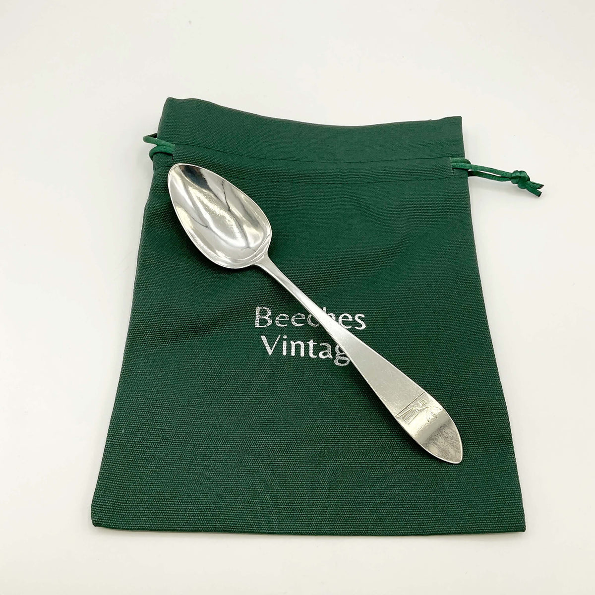 Antique 1700s Georgian sterling silver dessert spoon with ornate handle, from Beeches Vintage, showcasing detailed craftsmanship.