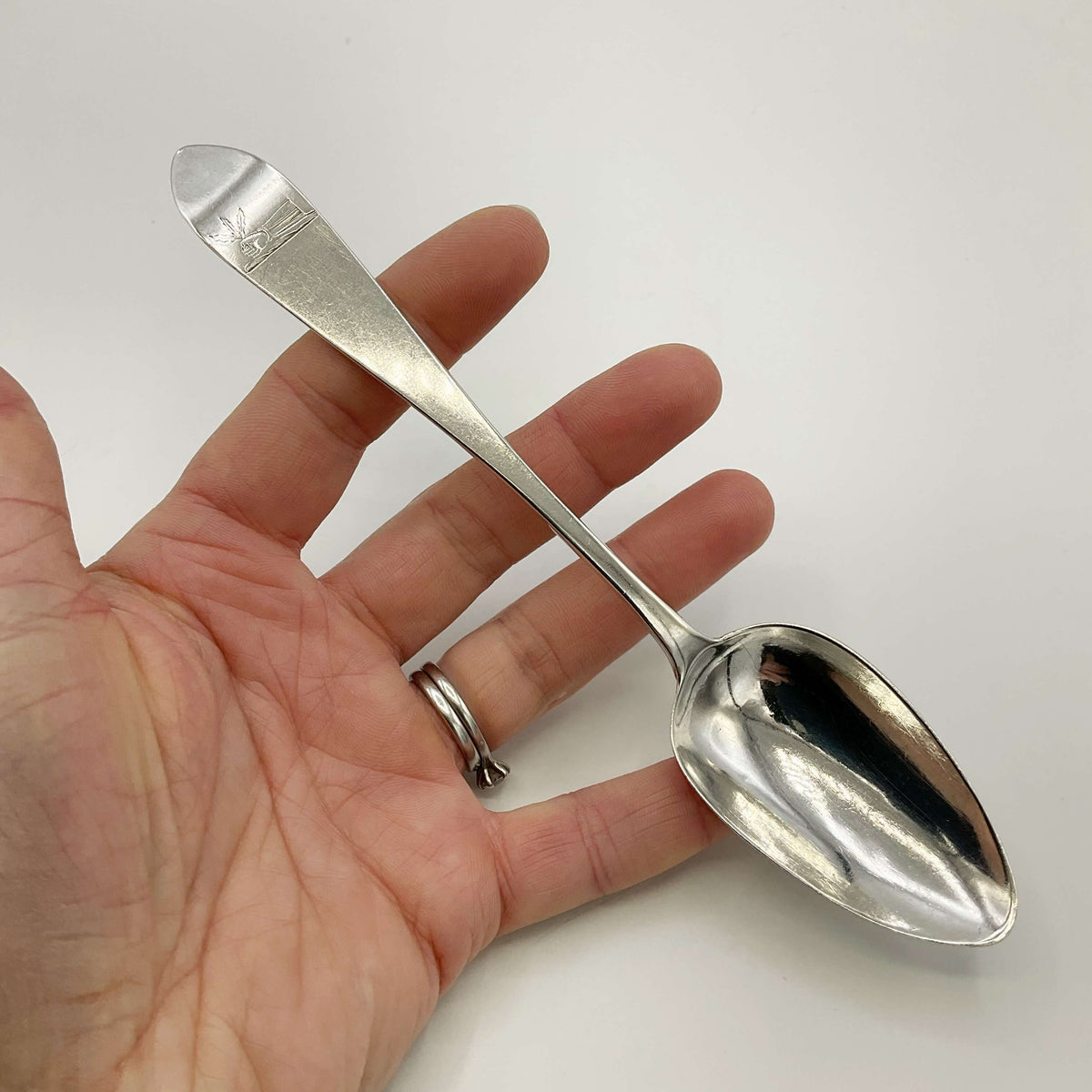 Antique 1700s Georgian sterling silver dessert spoon with ornate handle, from Beeches Vintage, showcasing intricate craftsmanship.