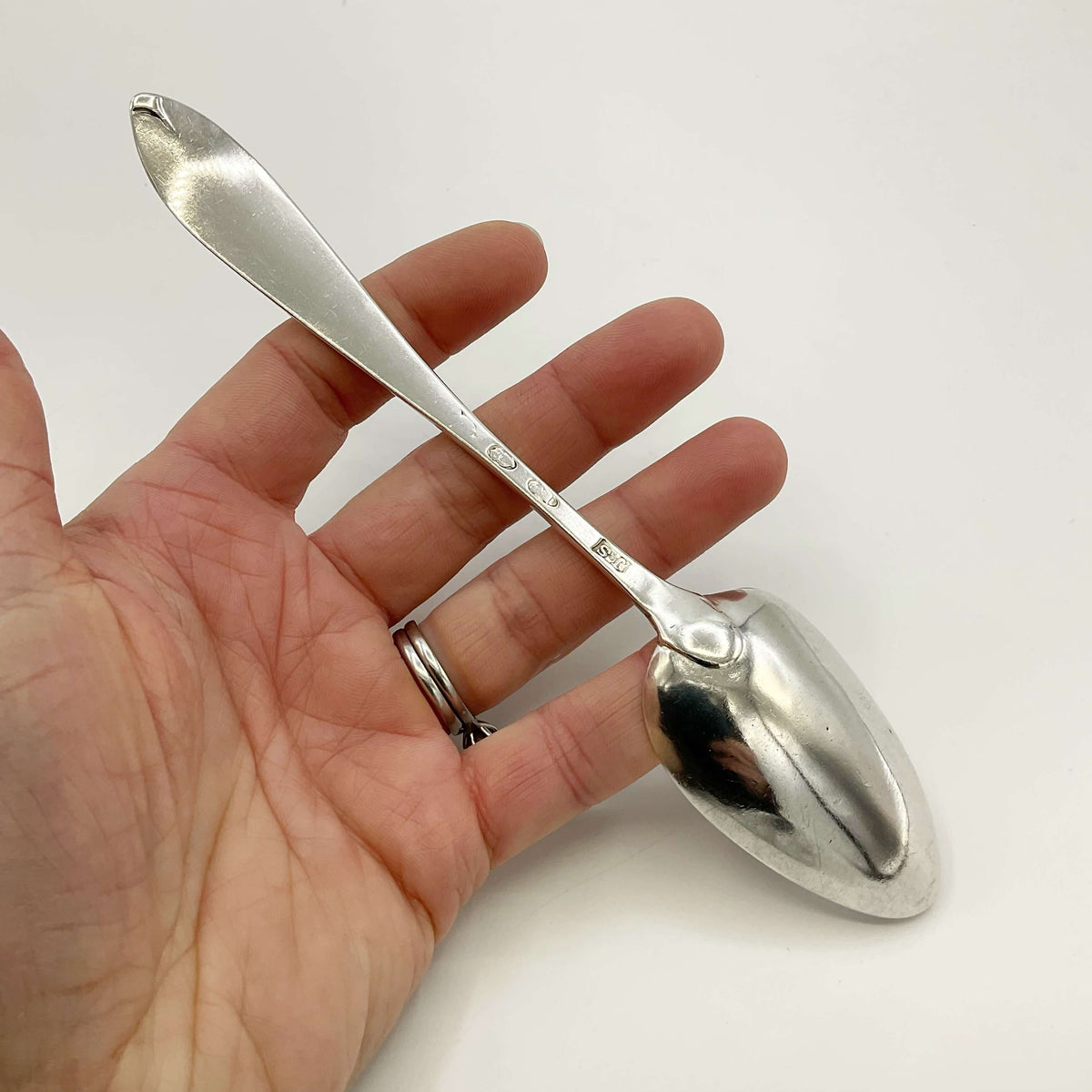 Antique 1700s Georgian sterling silver dessert spoon with ornate handle, by Beeches Vintage, showcasing intricate vintage craftsmanship.