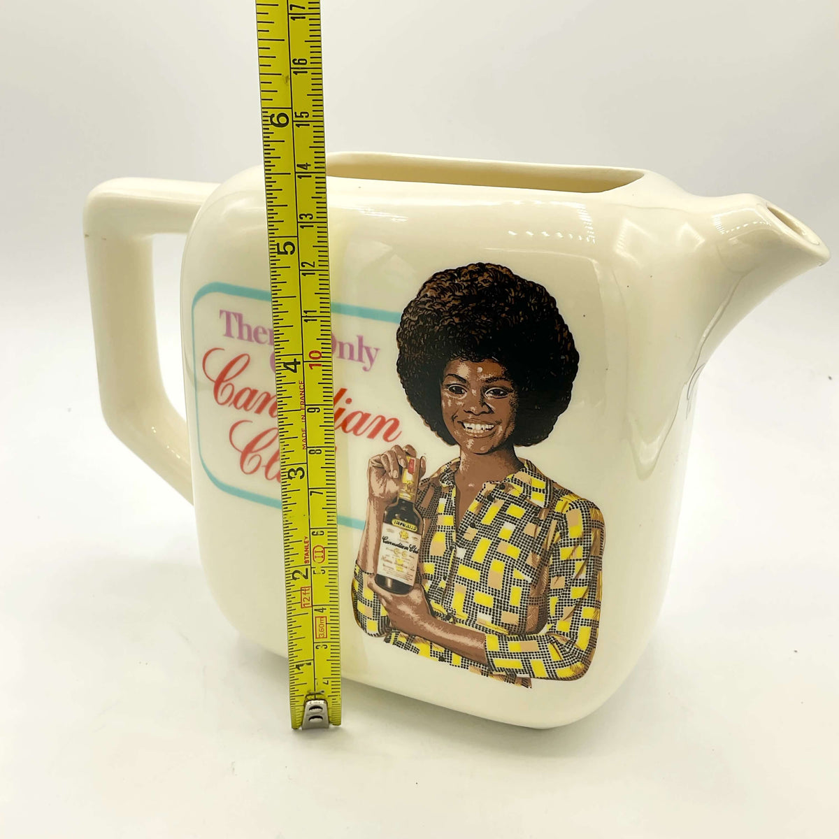 Side view of Canadian Club Whisky Water Jug  on a white background next to tape measure showing height as 13.5cm
