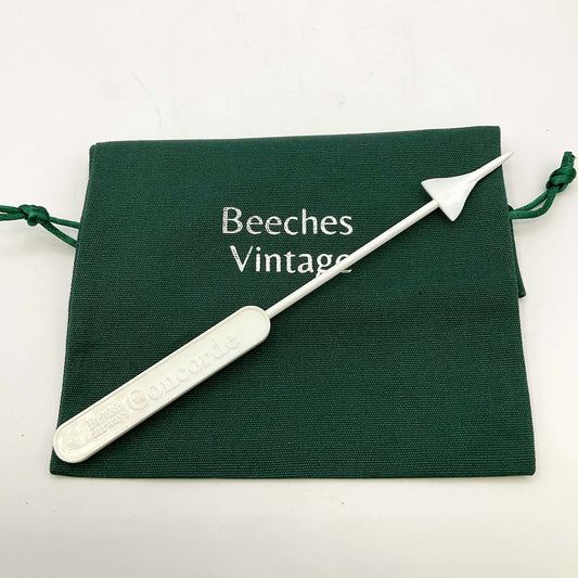 White Concorde Swizzle stick on a green gift bag and a white background 
