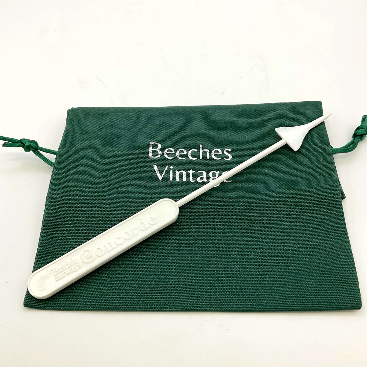 White Concorde Swizzle stick on a green gift bag and a white background 