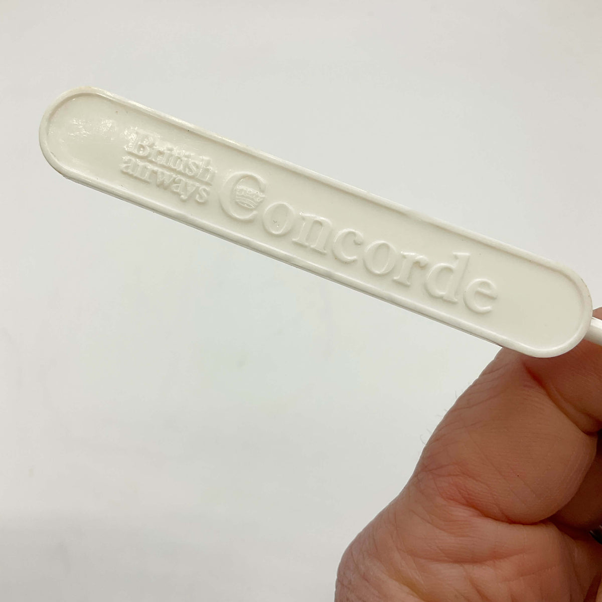 White Concorde Swizzle stick handle held in hand with a white background 