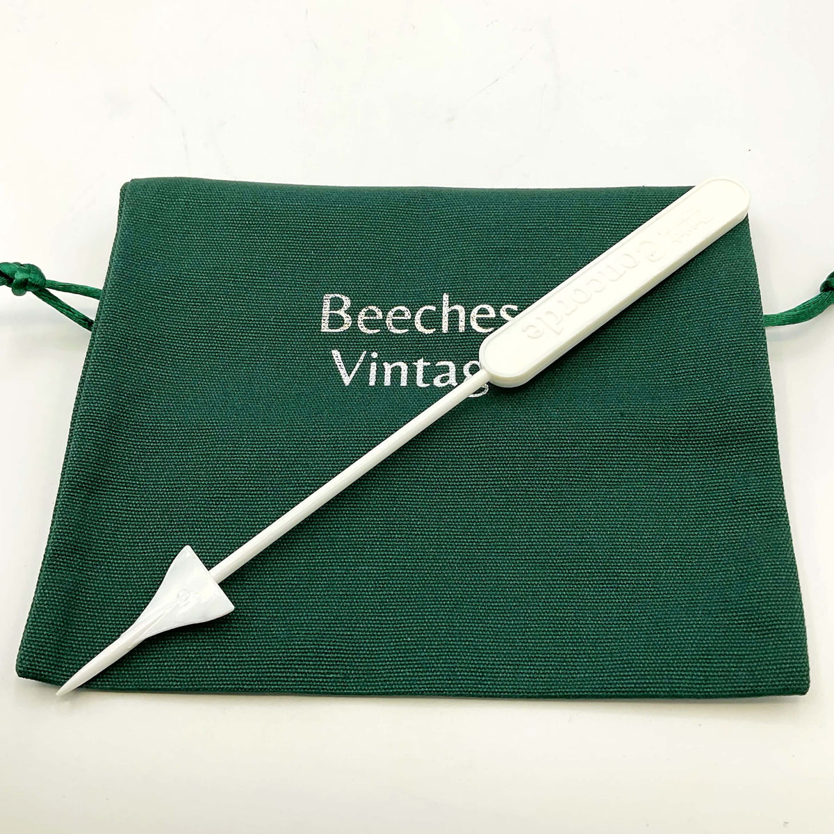 White Concorde Swizzle stick on a green gift bag and a white background 