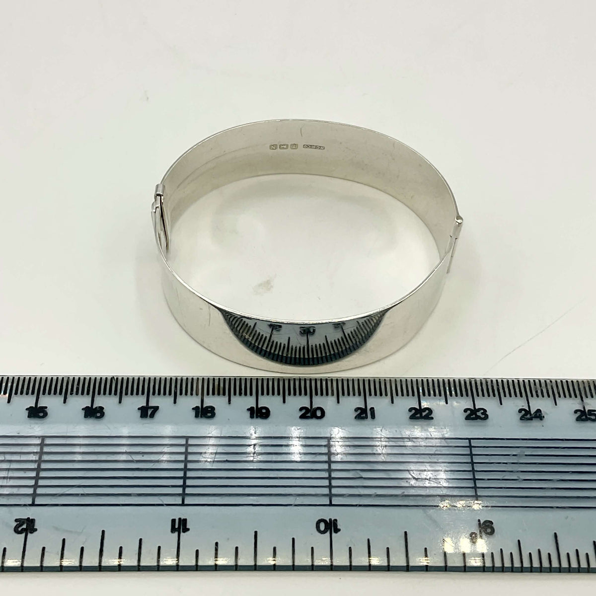 Silver Art Nouveau design bracelet next to a tape measure on a white background.