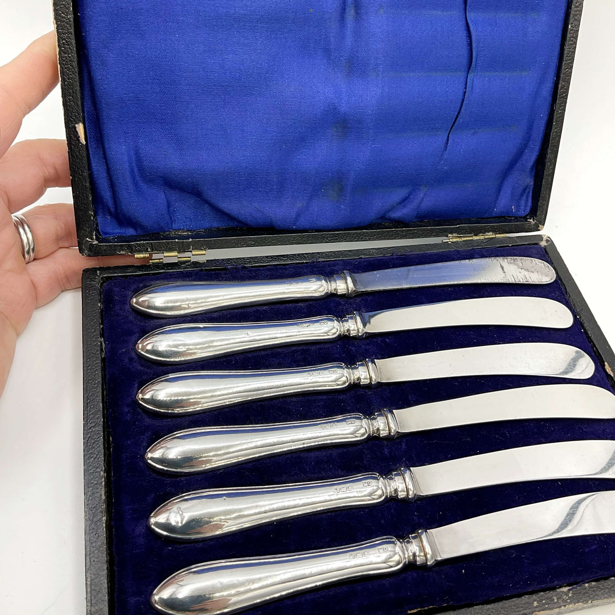 Antique set of silver tea knives in a presentation box with a white background showing a broken hinge