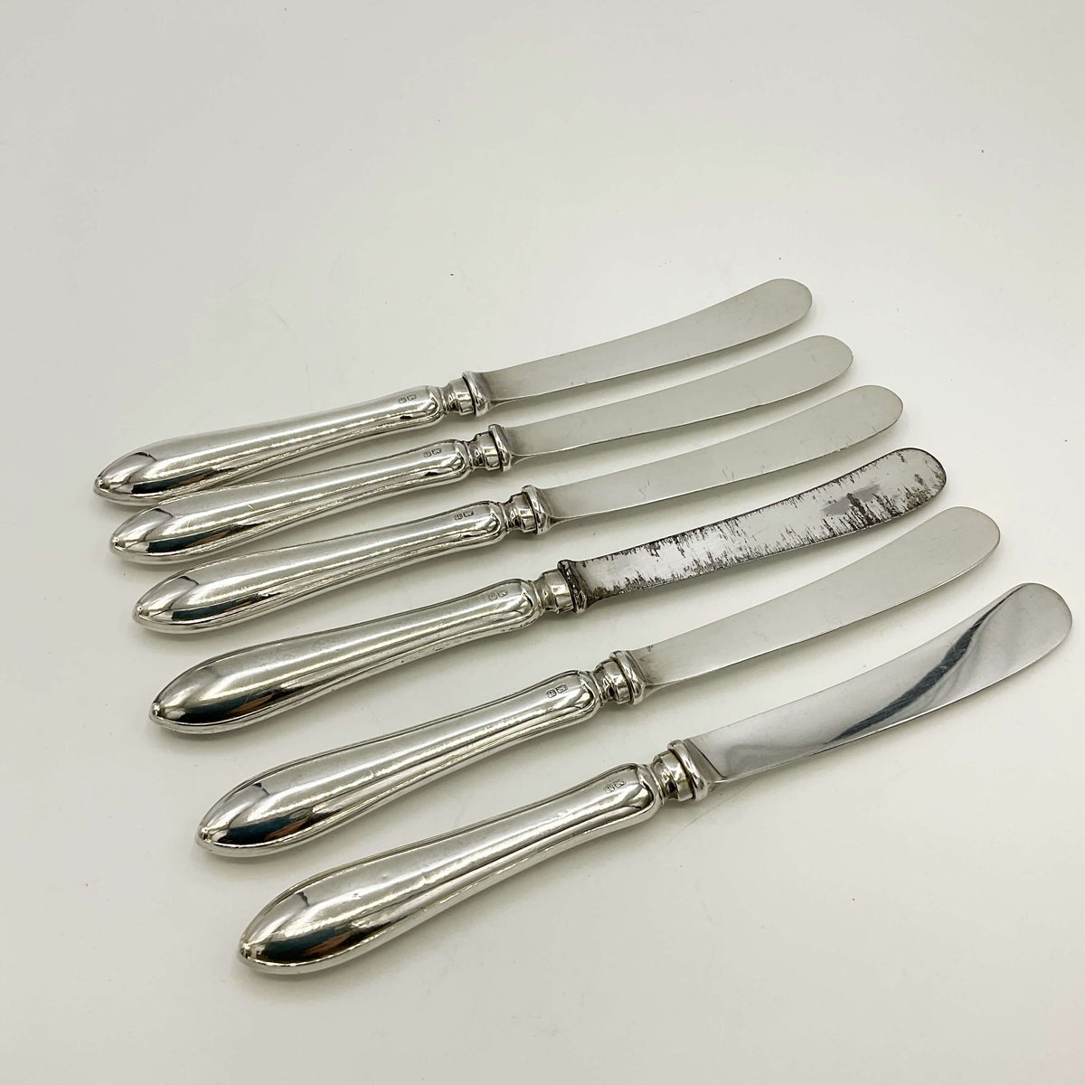 Antique set of silver tea knives with a white background