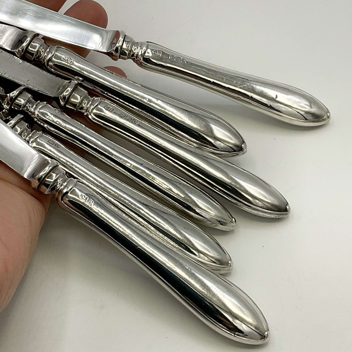 Antique set of silver tea knife handles with a white background