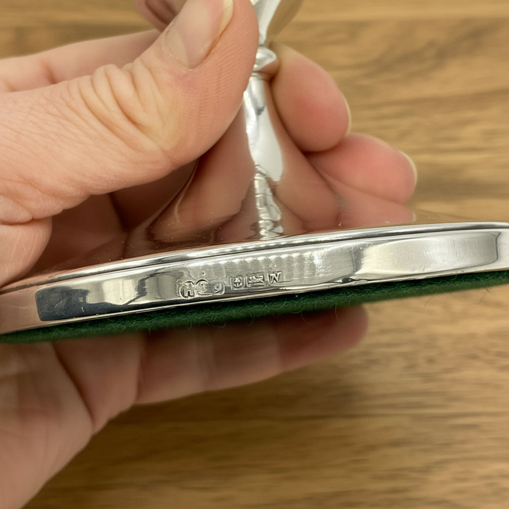 Hallmarks and maker’s mark on the side of a candlestick holder held in a hand