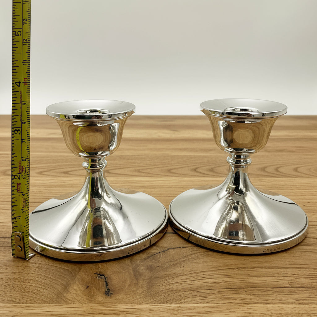 Pair of silver candlestick holders next to a tape measure showing the height as 8.2cm