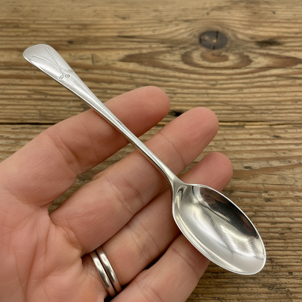 Silver coffee spoon held in a hand on coffee in the background 