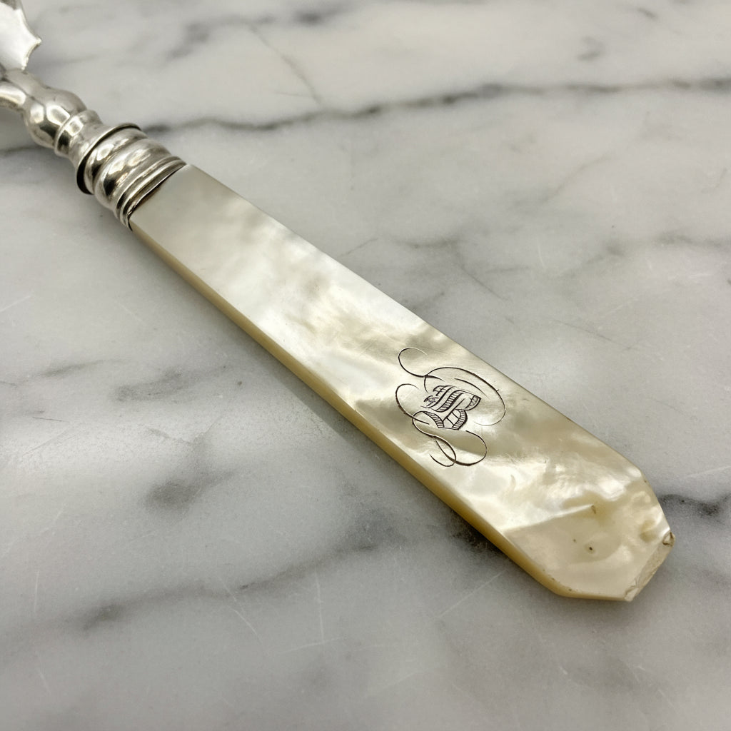 Antique silver and mother of pearl butter knife handle on a marble worktop
