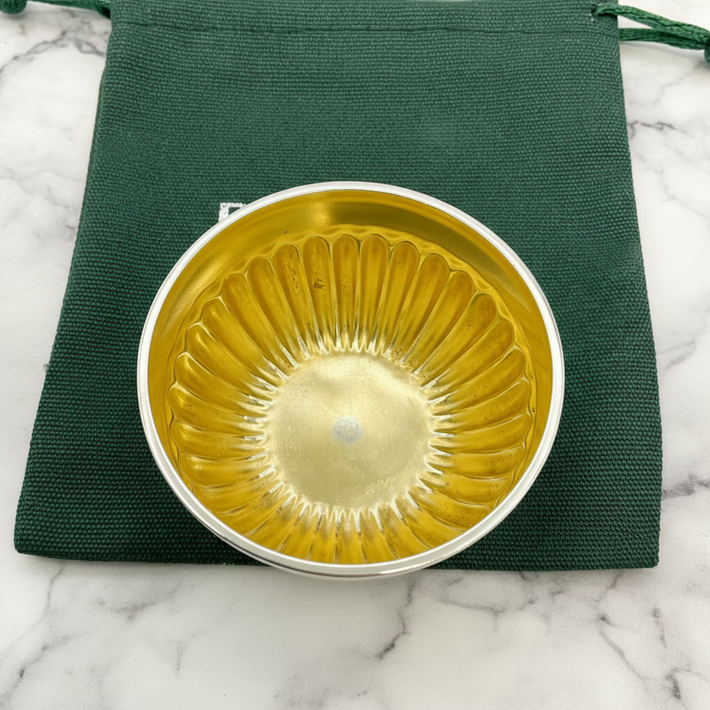 Gold and silver bowl on a green fabric and marble background