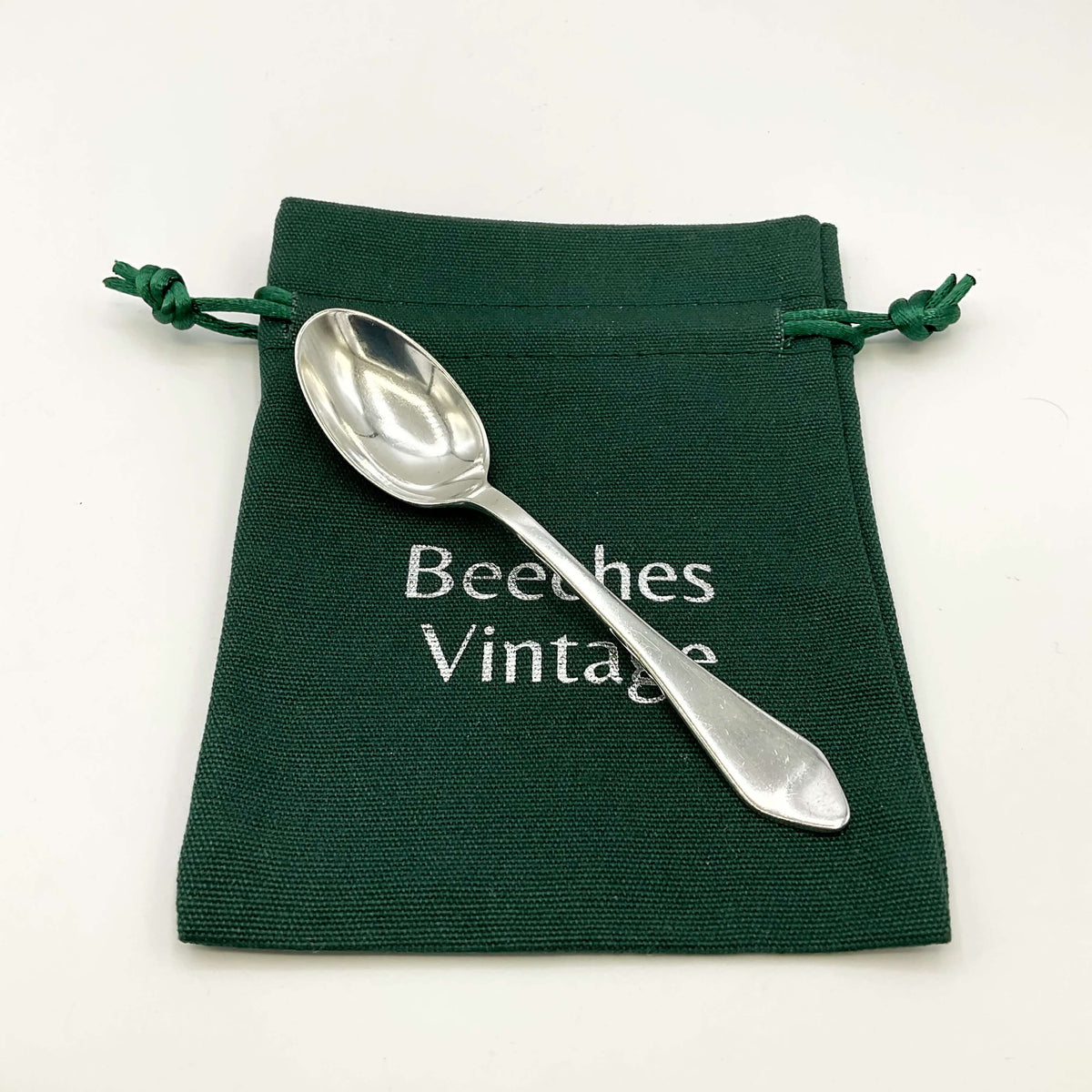 Silver coffee spoon on a green gift bag and white background 