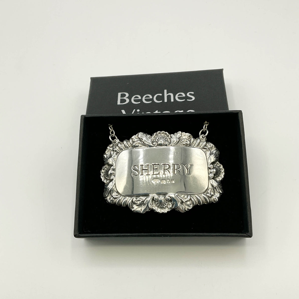Silver Sherry decanter label in  a black presentation box with a white background 
