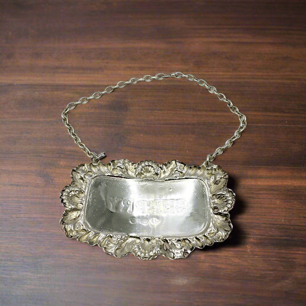 Back of silver Sherry decanter label on a wood table