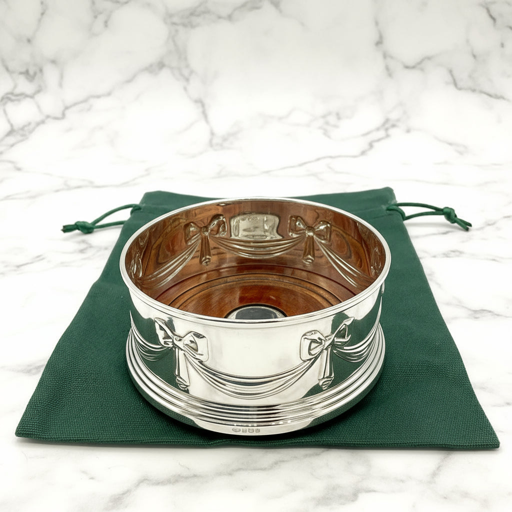 Silver coaster with decorative patterns on a green cloth background