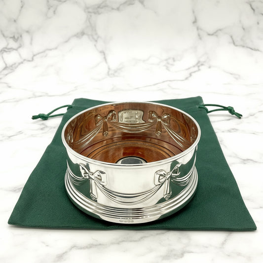 Silver coaster with decorative patterns on a green cloth background