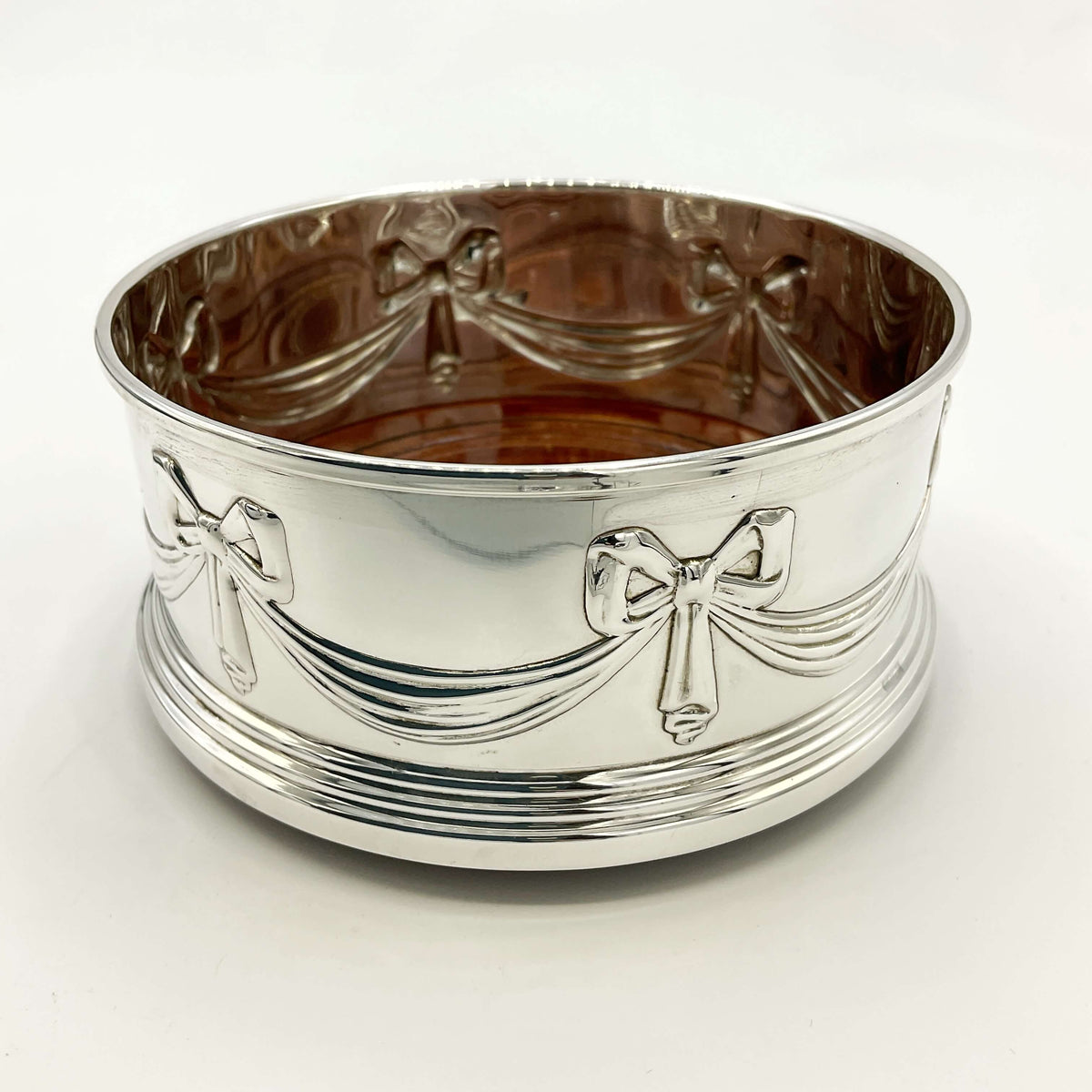 Silver bottle coaster with bow designs on a marble background